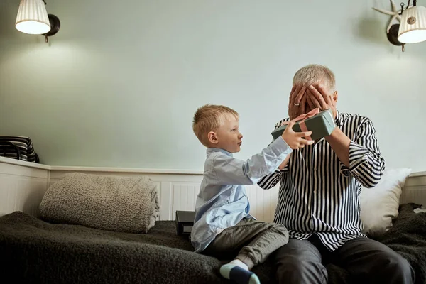 Γενιά. παππούς και εγγονός με κουτί δώρου κάθεται στον καναπέ στο σπίτι — Φωτογραφία Αρχείου