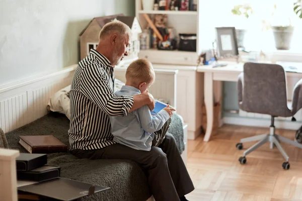 Dědeček a vnuk pomocí digitálního tabletu při sezení na gauči — Stock fotografie