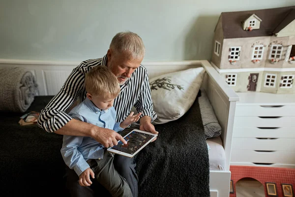 Дід і онук, використовуючи цифровий планшет, сидячи на дивані — стокове фото