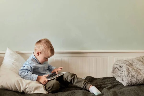 Niño con tableta digital sentado en el sofá, en la sala de estar — Foto de Stock