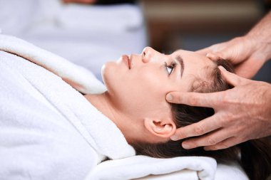 Güzeller güzeli genç bir kadın spa merkezinde kafa ve omuz bölgesine masaj yaptırıyor.