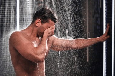 Yakışıklı adam duş alıyor, sıcak bir iş gününden sonra kendine geliyor..