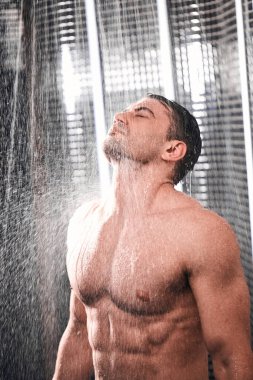 Yakışıklı adam duş alıyor, sıcak bir iş gününden sonra kendine geliyor..