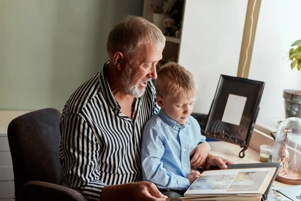 Avô e neto no sofá em casa. Avô e crianças assistindo fotos antigas — Fotografia de Stock