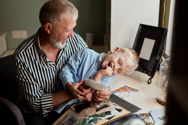 Abuelo y nieto en el sofá en casa. Abuelo y niños viendo fotos viejas —  Fotos de Stock