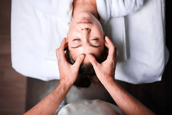 Mujer disfrutando de masaje facial anti envejecimiento. Foto al revés de la mujer relajante — Foto de Stock