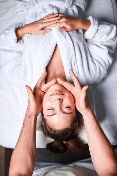 Женщине нравится антивозрастной массаж лица. Перевернутое фото расслабляющей женщины — стоковое фото