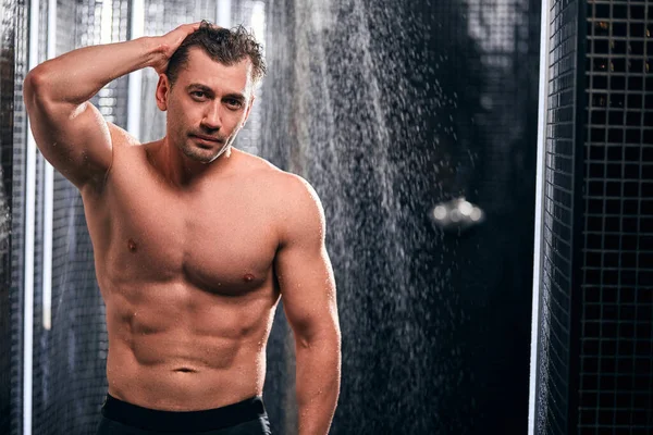 Hombre guapo tomando una ducha, refrescándose después de un día de trabajo caliente . — Foto de Stock