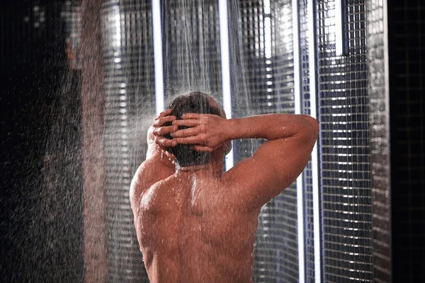 Przystojny mężczyzna bierze prysznic, odświeża się po gorącym dniu pracy. — Zdjęcie stockowe