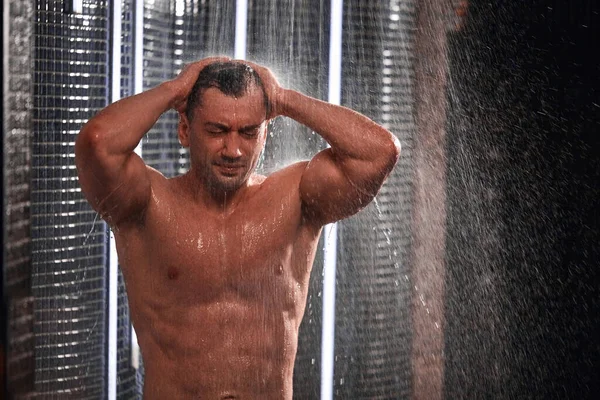 Hombre guapo tomando una ducha, refrescándose después de un día de trabajo caliente . — Foto de Stock