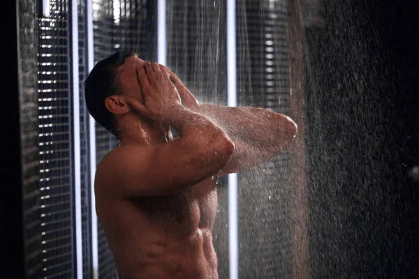 Hombre guapo tomando una ducha, refrescándose después de un día de trabajo caliente . — Foto de Stock