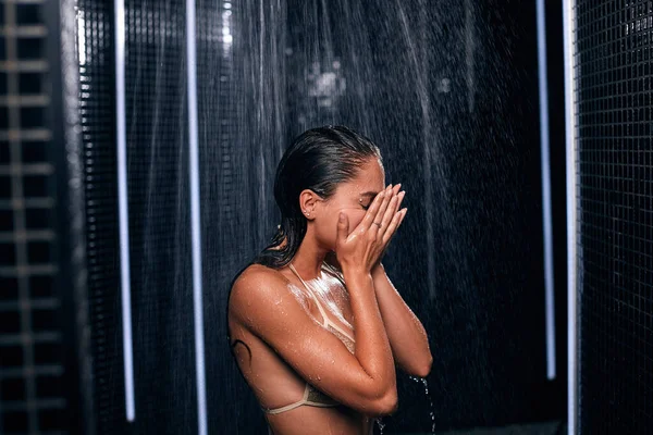 Mooie Kaukasische brunette vrouw nemen douche in haar zwart luxe badkamer. — Stockfoto