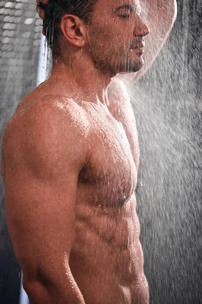 Hombre guapo tomando una ducha, refrescándose después de un día de trabajo caliente . — Foto de Stock