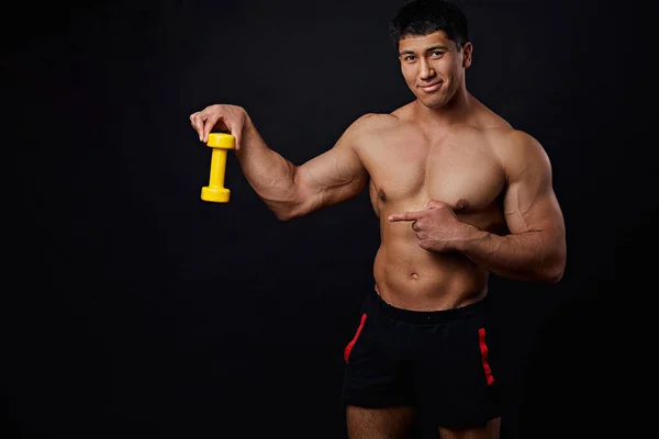 Silný sportovec drží malý žlutý činka a ukazuje někam — Stock fotografie