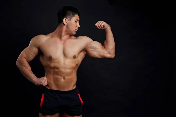 Fisiculturista ambicioso mostrando bíceps e tríceps . — Fotografia de Stock