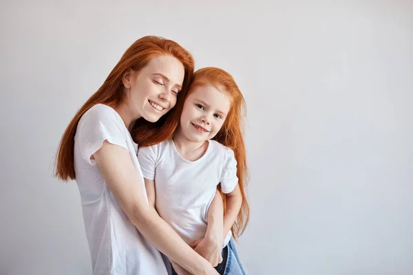 Krásné mladé červené vlasy matka objímající její roztomilé malé dítě. — Stock fotografie