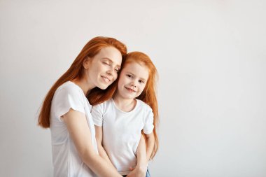 Güzel, genç, kızıl saçlı anne küçük bebeğine sarılıyor..