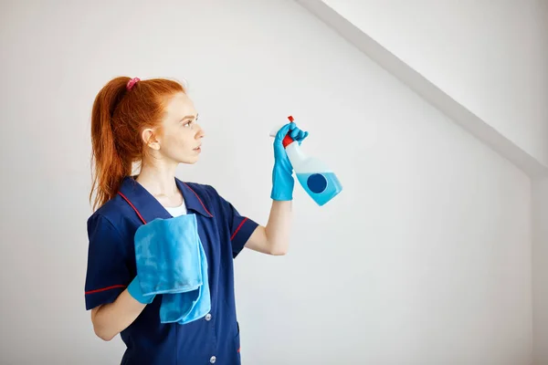 Huisvrouw met roodharige paardenstaart houdt stofdoek en ruitenwisser. — Stockfoto