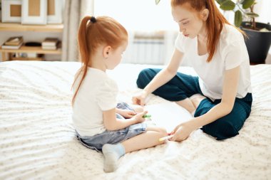Kapat. Anne kızının resim çizmesine yardım ediyor.