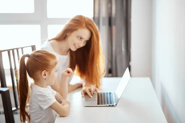 Červenovlasá maminka a její roztomilá dcera sledující kreslené filmy na notebooku — Stock fotografie