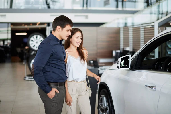 Young couple in elegant summer time clothes choose a new car at car dealership — Stock Photo, Image