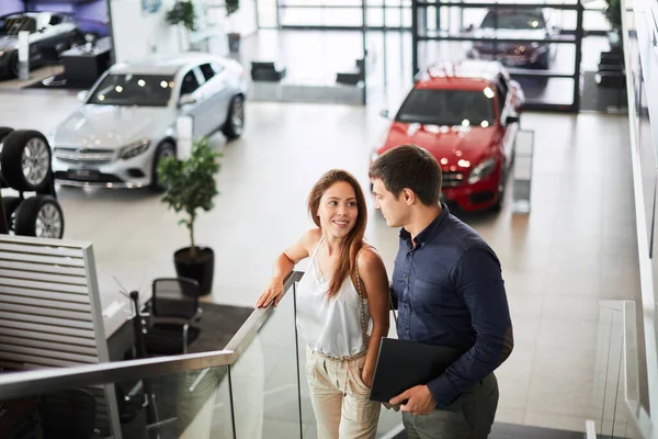 젊은 자동차 판매원이 여성 고객에게 차의 특징에 대해 말하는 모습 — 스톡 사진