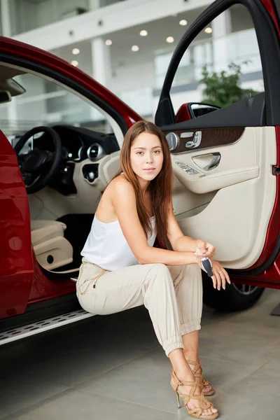 Lächelnde Frau wählt neues Auto im Autohaus und liest Eigenschaften — Stockfoto