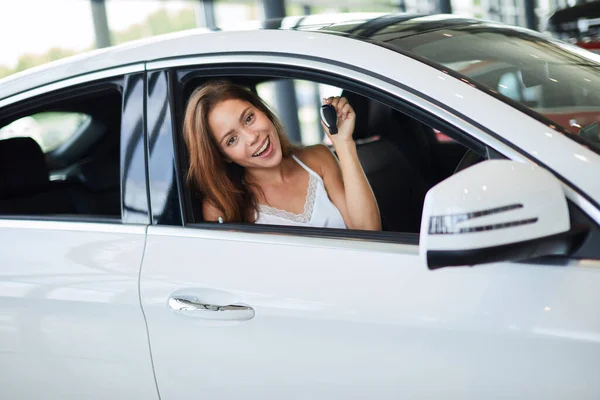 Boldog nő sofőr fehér autó tartja autó kulcsok az ő új autó az autó bemutatóteremben — Stock Fotó