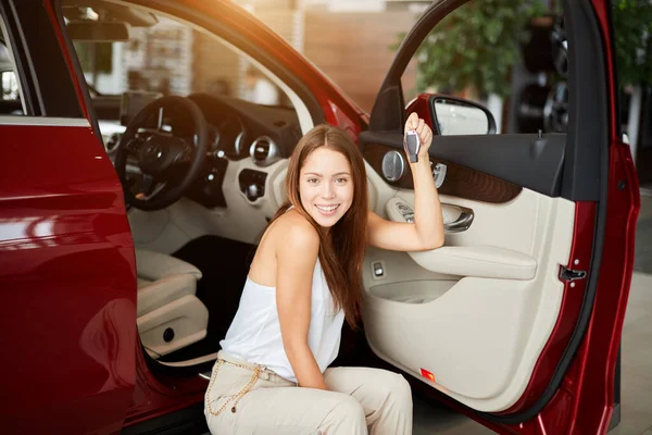 Glückliche Frau mit Schlüssel aus Neuwagen in Autoshow oder Salon — Stockfoto