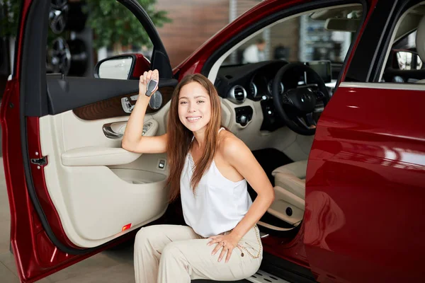 Glückliche Frau mit Schlüssel aus Neuwagen in Autoshow oder Salon — Stockfoto