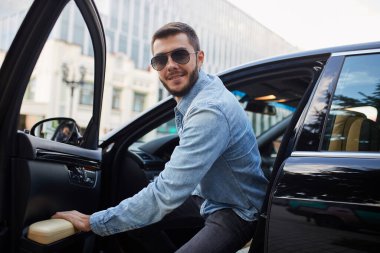 Havalı vahşi adam arabaya biniyor.