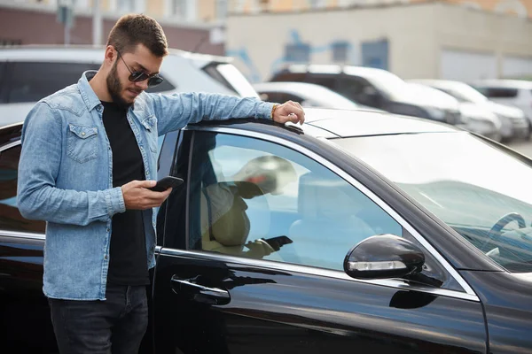 진지하게 차에 기대고 문자를 보내는 사람 — 스톡 사진