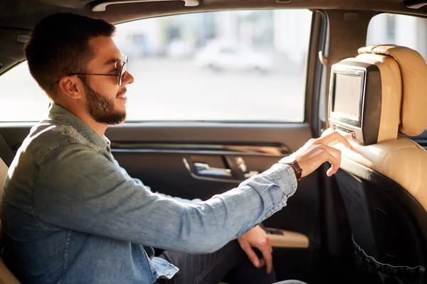 Young awesome man is watching TV in the car — Stock Photo, Image
