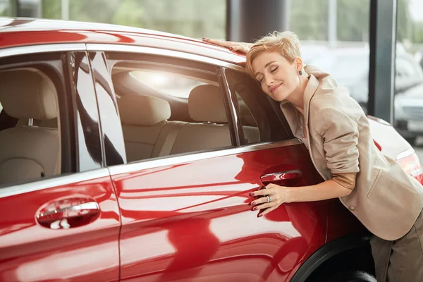 Glückliche Kaukasierin umarmt ihr neues Auto im Autohaus — Stockfoto