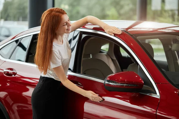 Boldog kaukázusi nő átöleli az új autóját az autókereskedésben — Stock Fotó