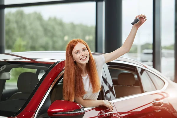 Junge glückliche Frau überrascht von einem neuen Auto im Autohaus, Geschenk ihres Mannes — Stockfoto