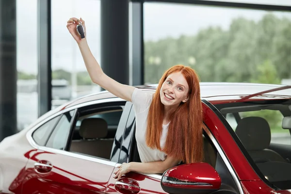 Junge glückliche Frau überrascht von einem neuen Auto im Autohaus, Geschenk ihres Mannes — Stockfoto