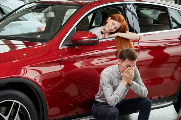 Boldog nő ünnepli a vásárlás az új drága autó, míg a férfi frusztrált — Stock Fotó