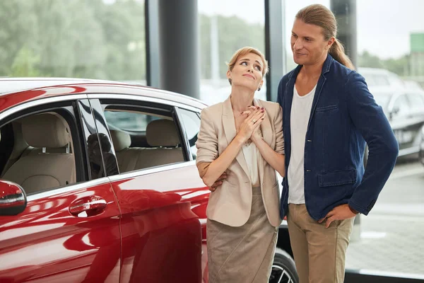 幸せな若い妻を求めています新しい車を購入するために彼女のためにディーラー. — ストック写真