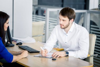 Araba perakende ofisinde satıcı erkek ve müşteri kadın.