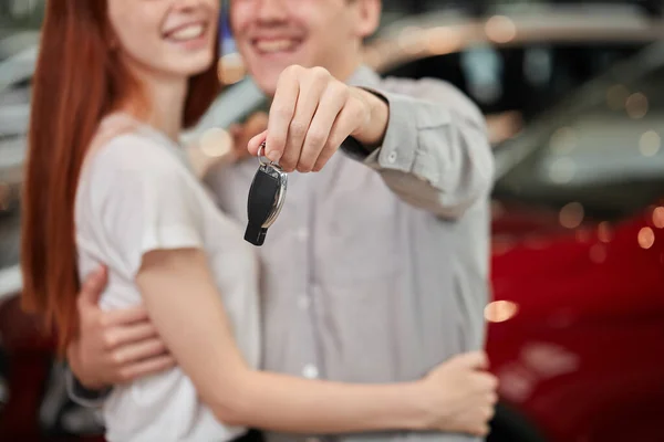 Красива пара тримає ключ від своєї нової машини, дивлячись на камеру і посміхаючись — стокове фото