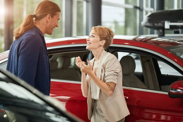 Feliz joven esposa pidiendo comprar un coche nuevo para ella en el concesionario . — Foto de Stock