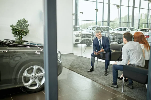 Feliz hermosa pareja está comprando un coche nuevo en la concesionaria. Consejo familiar — Foto de Stock