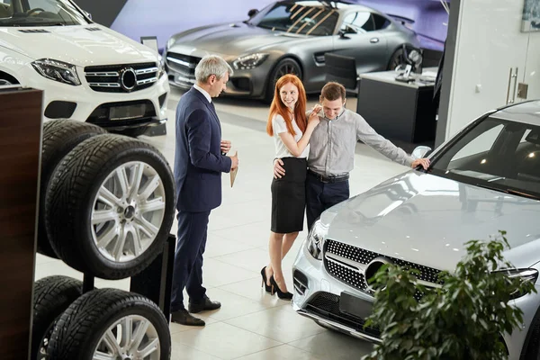 汽车销售经理向车行的顾客讲述汽车的特点 — 图库照片
