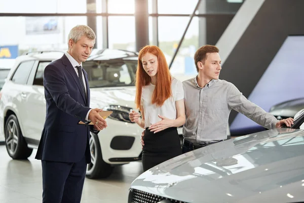 Araba satış müdürü arabanın özelliklerini galerideki müşterilere anlatıyor. — Stok fotoğraf
