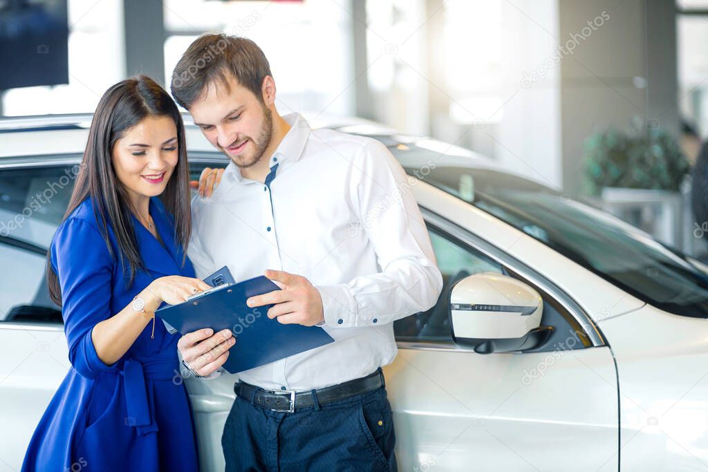 Happy couple choosing a car in dealership