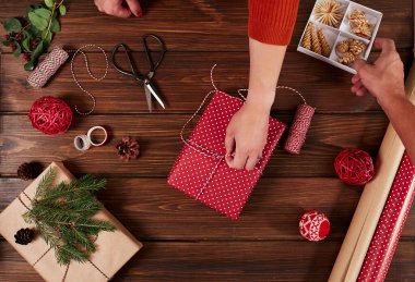 Kadın hediye paketi ve ahşap masa üzerindeki dekorasyon malzemeleri, yakın, üst görünüm.