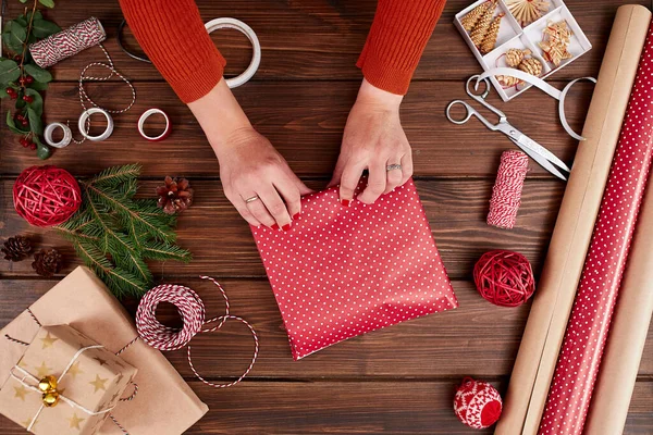 女人的手把圣诞礼物包在深色的木制背景上. — 图库照片