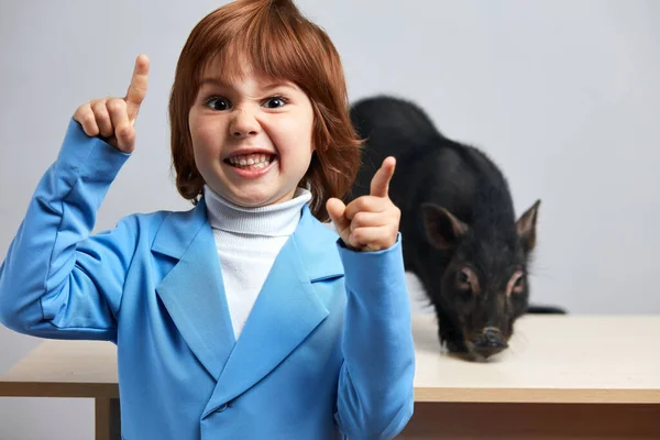 Adorable niño, niño bonito con lechoncito negro posando en interiores — Foto de Stock