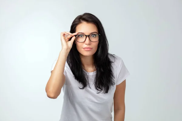 Schockierte hübsche Frau berührt ihre Brille und blickt in die Kamera — Stockfoto